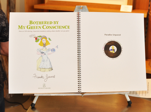 Franke James holding big book copy of Bothered by My Green Conscience; photo by Central Image Agency